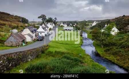 Plockton, Schottland, Großbritannien - 22. September 2013: Traditionelle Hütten säumen die Dorfstraße von Duirnish, neben einem kleinen Bach, im Lochalsh Bezirk Stockfoto