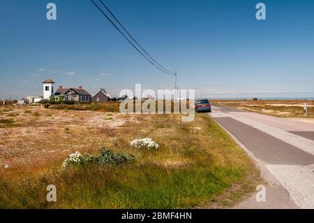 Dungeness, England, UK - 8. Juni 2013: Eine Reihe von niedrigen Holzhäusern ist entlang der Straße zwischen Dungeness und Lydd-on-Sea in der rauen flachen envi verstreut Stockfoto