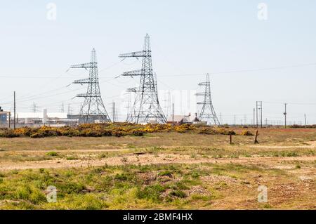 Dungeness, England, Großbritannien - 8. Juni 2013: Stromleitungen und Pylone in der Nähe des Kernkraftwerks Dungeness an der Küste von Kent. Stockfoto