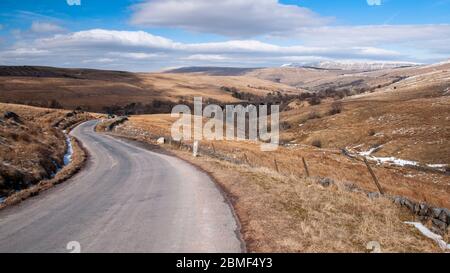 Eine einspurige Landstraße klettert von Dentdale über dem Dent Head Viadukt auf der Settle-Carlisle Railway Line in die hügelige Moorlandschaft von Stockfoto