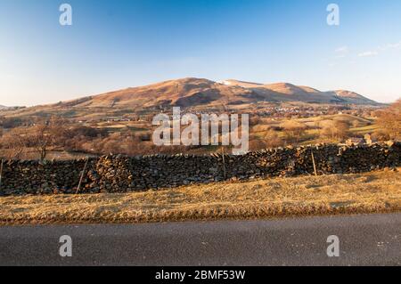 Die schneebedeckten Howgill Fells Hills erheben sich und binden die Stadt Sedbergh im Yorkshire Dales National Park. Stockfoto