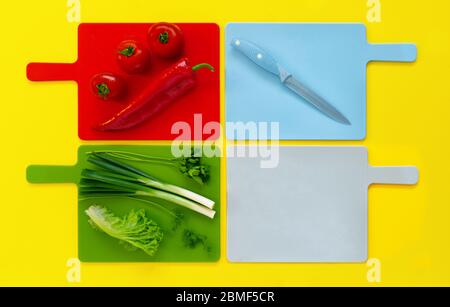 Flache Lage von farbigen Schneidebretter mit grünen frischen Gemüse , frische Tomaten und rote Paprika Kapia bunte minimalistische Lebensmittel kopieren Raum Küche m Stockfoto