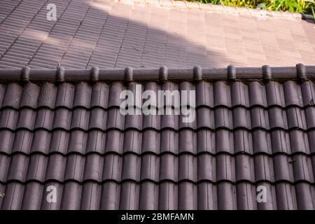 Braunes Naturziegeldach. Moderne Dachmaterialien. Dach des Hauses, Naturdachziegel gegen den blauen Himmel. Gebäude Stockfoto