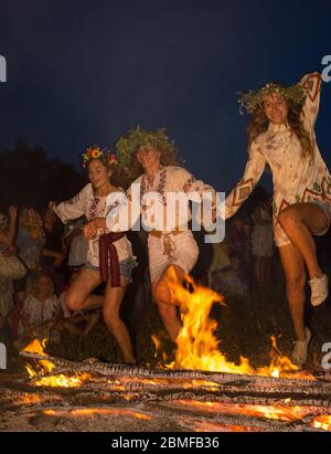 Pirogiv, Oblast Kiewskaja/Ukraine - 07.06.2013. Mädchen in ukrainischen Hemden springen über das Feuer. Ivan Kupala Urlaub. Stockfoto