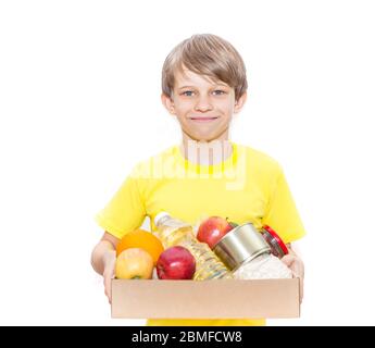 Glücklicher Junge hält eine Kiste mit Nahrung, isoliert auf weißem Hintergrund. Lieferung von Lebensmitteln. Freiwilliger bringt einen Lebensmittelkasten. Stockfoto