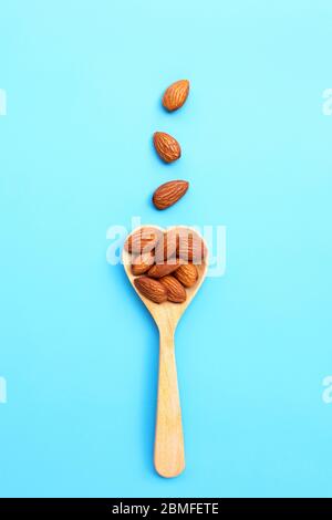 Mandeln auf Herz Form Holzlöffel auf blauem Hintergrund. Draufsicht Stockfoto