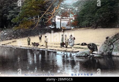 [ 1900er Japan - Ise Grand Shrine ] - Schrein Besucher reinigen ihre Hände, bevor sie den heiligen Naiku Schrein am Ise Grand Shrine (伊勢神宮, Ise Jingu) besuchen, ein schintoistischer Schrein, der Sonnengöttin Amaterasu gewidmet, in Ise, Präfektur Mie. Vintage-Postkarte des 20. Jahrhunderts. Stockfoto