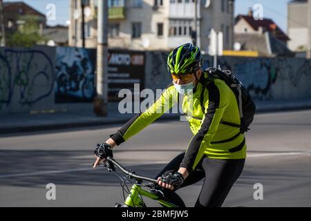 UKRAINE, KIEW - 25. April 2020: Professionelle Fahrradfahrer fährt mit einer medizinischen Maske, um eine bakterielle Infektion Corona Virus oder Covid 19 epi zu verhindern Stockfoto