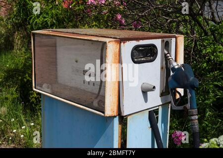 Eine rostige, altmodische Gaspumpe vor einer verlassenen Tankstelle Stockfoto