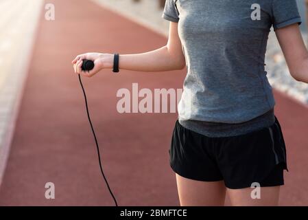 Frau, die ein Springseil auf einer Laufstrecke hält, bevor sie im Freien Fitness trainiert Stockfoto