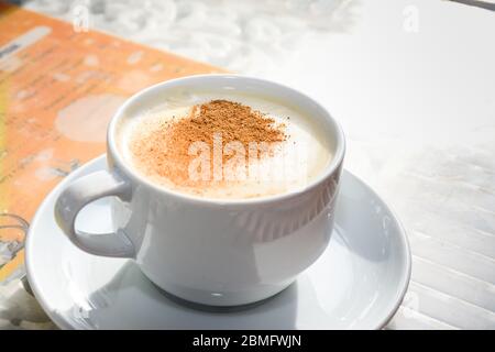 Weiße Tasse Salep milchig heißes Getränk der Türkei mit Zimtpulver und Sticks gesunde Würze und Herbst Winterblatt auf weißen rustikalen Vintage-Holztisch Stockfoto