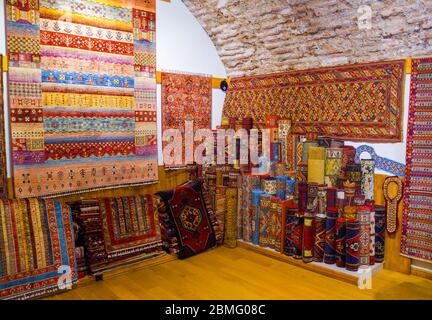 Stapel von schönen handgefertigten Teppichen auf dem offenen Markt Basar. Traditionelles türkisches Design. Stockfoto