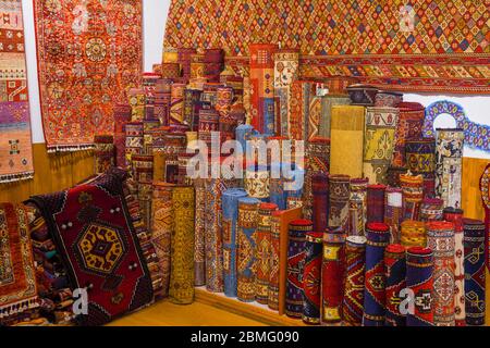 Stapel von schönen handgefertigten Teppichen auf dem offenen Markt Basar. Traditionelles türkisches Design. Stockfoto