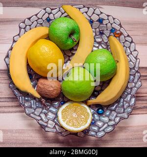 Symmetrische Draufsicht auf verschiedene Früchte in einer Glasschale von vielen Glassteinen Stockfoto