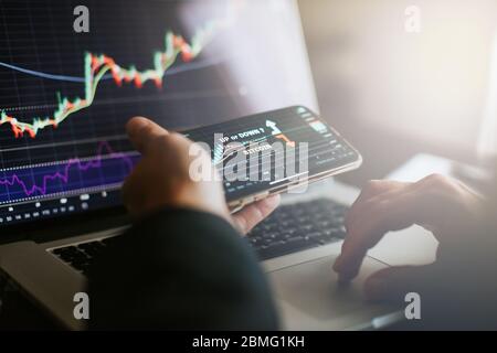 Aktienhändler analysieren Gewinnchancen investieren Bitcoin. Krypto-Händler mit Handy und Laptop im Innenbereich. Stockfoto