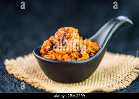 Würzige knusprige Garnelen Chili Paste in schwarzem Löffel auf Burlap und dunklem Hintergrund Stockfoto