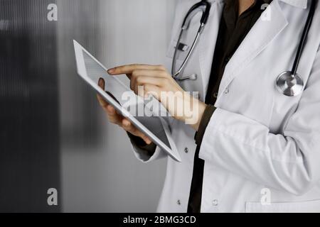 Unbekannter weiblicher Arzt mit Tablet-Computer in der Klinik. Perfekter medizinischer Service im Krankenhaus. Medizinkonzept Stockfoto