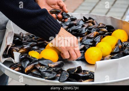 Gekochte Muscheln in Keramikschale garniert mit frischen Kräutern und Zitrone. Leckeres Meeresfrüchte-Menü, ideal zum Mittag- oder Abendessen, Vorspeise zum Brunch oder Buffet Stockfoto