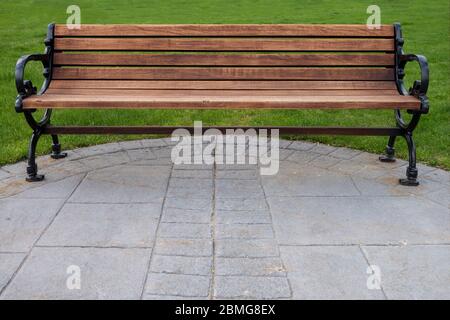 park bewaldeten und schwarzen Gusseisen klassische Bank mit grünem Gras und Zement Gehweg Stockfoto