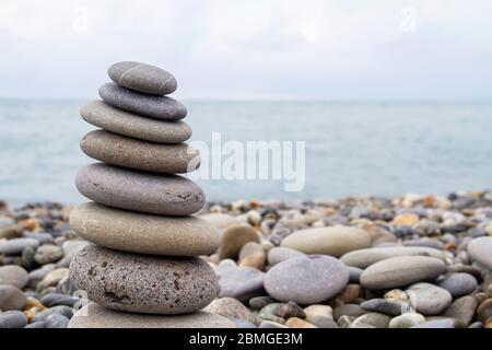 Pyramide aus Meeressteinen am Strand am Kiesstrand. Konzept der Harmonie und Balance. Stockfoto