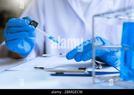 Wissenschaftler tragen Labormantel und Schutzkleidung arbeiten mit Forschung oder machen Untersuchungen mit Reagenzgläsern in Experiment, Labor und Entwicklung Stockfoto