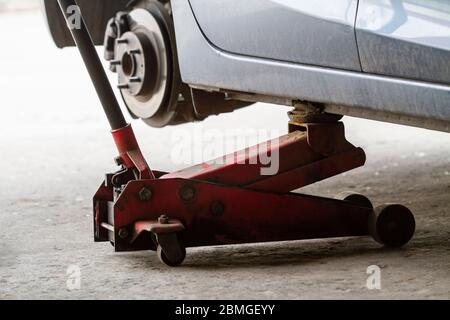 Wagenheber ersetzt die Räder eines Autos und hält die Karosserie in angehobener Position. Auto ohne Rad und heben Sie durch hydraulische, warten auf Reifenwechsel. Stockfoto