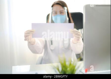 Weibliche Doctor in Uniform zeigt eine leere Papier Beschilderung leere Tafel weiß. Epidemie-Pandemie-Verbreitung Coronavirus 2019-ncov sars Covid-19 Grippevirus Konz Stockfoto