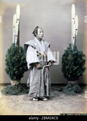 [ 1880er Japan - Japanischer Samurai ] - Samurai mit zwei Schwertern zwischen den Neujahrsdekorationen. Vintage Albumin-Fotografie aus dem 19. Jahrhundert. Stockfoto
