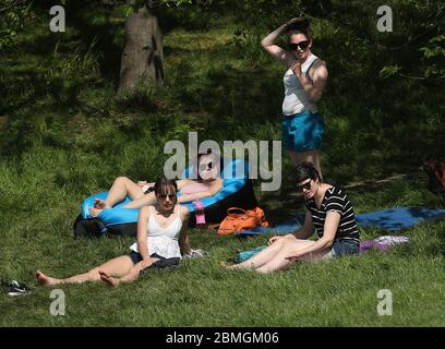 Eine Gruppe Sonnenanbeter wird von einem Polizeibeamten in Greenwich Park, London, aufgefordert, sich weiter zu bewegen, da Großbritannien weiterhin gesperrt ist, um die Ausbreitung des Coronavirus einzudämmen. Stockfoto