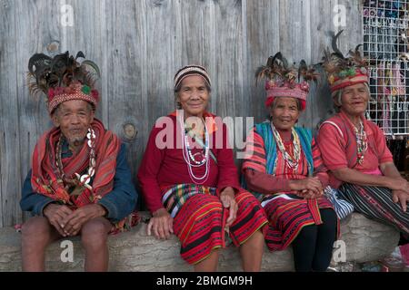 Banaue, Philippinen - Februar 2012: Gruppe älterer Menschen in traditioneller Kleidung auf einem Holz sitzend Stockfoto