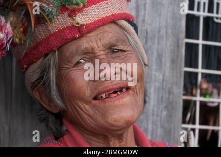 Banaue, Philippinen - Februar 2012: Ältere Frau in traditioneller Kleidung vor einer Holzwand Stockfoto