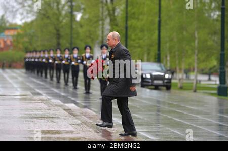 Moskau, Russland. Mai 2020. Der russische Präsident Wladimir Putin trägt einen Strauß roter Rosen zum 75. Jahrestag des Sieges über Nazi-Deutschland im Zweiten Weltkrieg, am Grab des unbekannten Soldaten entlang der Kreml-Mauern am 9. Mai 2020 in Moskau, Russland. Die jährliche Militärparade und Kundgebung am Siegestag wurde wegen der Coronavirus-Pandemie abgesagt. Kredit: Alexei Druzhinin/Kreml Pool/Alamy Live News Stockfoto