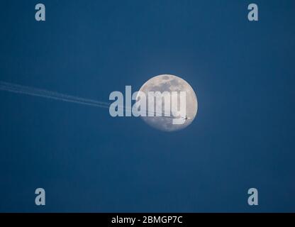 Ein Passagierflugzeug der Allegiant Airlines fährt vor Vollmond in großer Höhe. Stockfoto