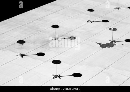 Schwarz-Weiß-Bilder von kleinen Metalltischen mit Schatten auf Zement schaffen Lichtmuster. Stockfoto