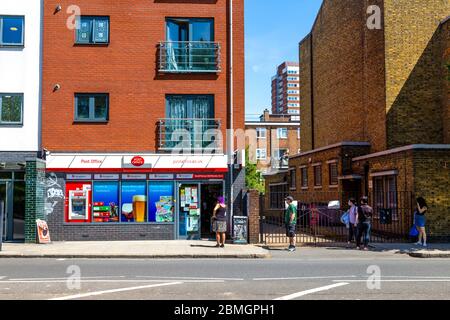 9. Mai 2020, London, Großbritannien - Menschen in einer Schlange zum Mile End Postamt respektieren soziale Distanzierung 2 m Entfernung Regeln Stockfoto