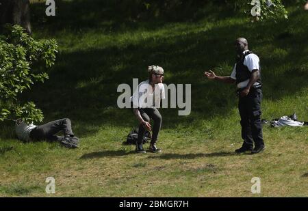 Ein Polizist zieht Sonnenanbeter in Greenwich Park, London, um die Ausbreitung des Coronavirus zu verhindern, während Großbritannien weiterhin gesperrt wird. Stockfoto