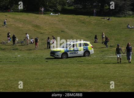 Polizeibeamte in einem Streifenwagen bewegen Sonnenanbeter in Greenwich Park, London, während Großbritannien weiterhin gesperrt wird, um die Ausbreitung des Coronavirus einzudämmen. Stockfoto