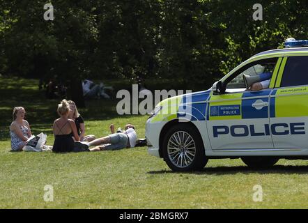 Polizeibeamte in einem Streifenwagen bewegen Sonnenanbeter in Greenwich Park, London, während Großbritannien weiterhin gesperrt wird, um die Ausbreitung des Coronavirus einzudämmen. Stockfoto