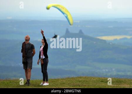 Kozakov, Tschechische Republik. Mai 2020. Ein Paar steht auf der Aussichtsterrasse und beobachtet einen Paragleiter, der über den Kozakov (100 Kilometer nördlich von Prag) in der Tschechischen Republik fliegt. Paragliding ist ein Freizeit- und Wettkampfsport. Der Pilot sitzt in einem Gurtzeug unter einem Stoffflügel, dessen Form durch den Druck der Luft gebildet wird, die in die Lüftungsschlitze vor dem Flügel eindringt. Kredit: Slavek Ruta/ZUMA Wire/Alamy Live News Stockfoto