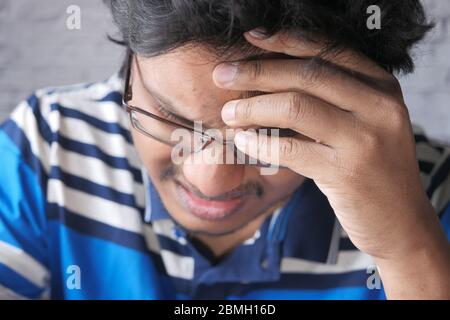 Nahaufnahme eines jungen Mannes, der Kopfschmerzen hat. Stockfoto