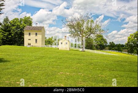 Zwei Schretttafelgebäude; Ebene; Wasserhaus, 1833, Brüder-Badehaus, 1860, Shaker-Dorf von Pleasant Hill; ländliche Szene; grünes Gras; weißer Zaun Stockfoto