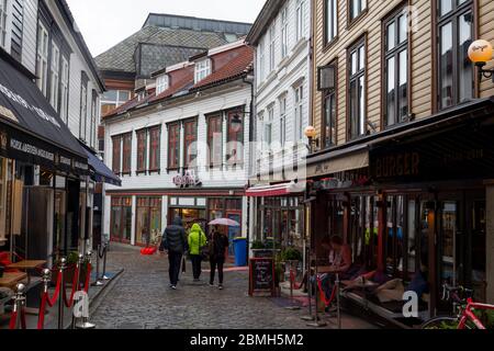 Stavanger, Norwegen - 12. August 2019: Menschen, die auf einer Terrasse in einer belebten Straße im Zentrum von Stavanger, Norwegen, spazieren und sitzen Stockfoto