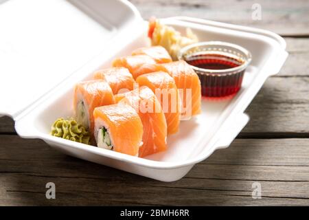 Schachtel mit Rollen Philadelphia Sojasauce und Wasabi auf Holzgrund. Japanische Küche. Lieferung von Lebensmitteln. Stockfoto