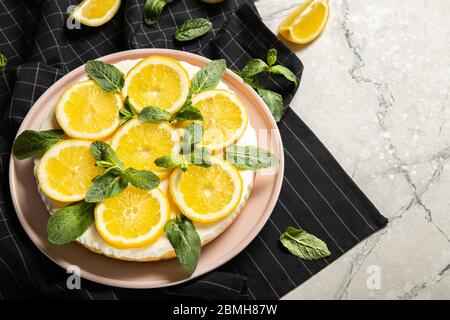 Teller mit köstlichem Käsekuchen und Zitronen auf dem Tisch Stockfoto
