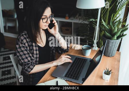 Junge Frau, die in ihrem Home Office am Telefon telefoniert. Work from Home Konzept Stockfoto