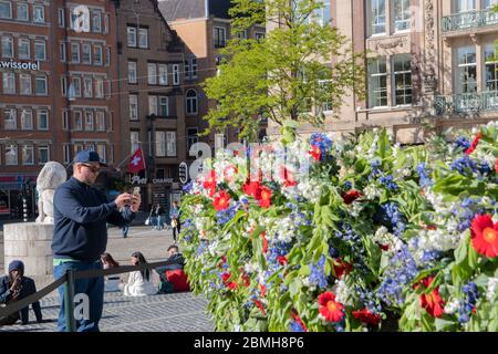 Mann, der am 4. Mai 2020 in Amsterdam, Niederlande, auf der Statue zur Erinnerung an die Toten Bilder aufnahm Stockfoto