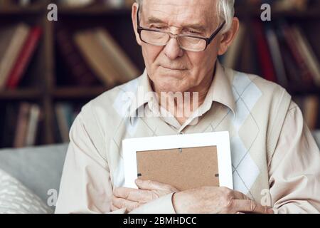Senior Mann allein sitzt in der Bibliothek Umarmung Foto nachdenklich Nahaufnahme Stockfoto