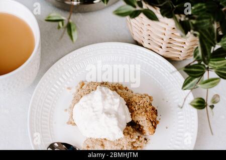 Süßes Leckerli Apfelkuchen und Eis Dessert, Apfelstreusel Creme, Tee, Nachmittagstee, entspannendes Konzept Blogging Foto, weiße Platte, Essen, Essen Stockfoto