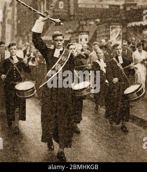 Ein historisches Pressefoto der Band von Christ's Hospital (Blue Coat School) in der Nähe von Horsham, Großbritannien, die in ihren traditionellen Kostümen marschiert.die Uniformen der Jungen haben sich seit Tudor Zeiten nicht verändert und bestehen aus einem langen blauen (Symbol der Nächstenliebe) Gürtel Mantel, passende Kniehosen, Gelbe Socken und weiße Nackenbänder. Mädchen sind auch zugelassen und tragen ähnliche Uniformen, aber mit einem geflochtenen Rock. Uniformen werden kostenlos zur Verfügung gestellt, eine Tradition aus der Frühzeit, als die Schule ‘Vaterlose und arme Kinder’ erzog und die Uniformen aus Spenden zur Verfügung gestellt wurden. Die Schule ist jetzt kostenpflichtig. Stockfoto