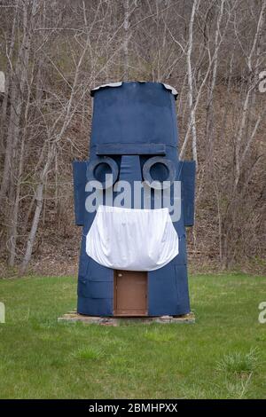 Palatine Bridge, NY: Sperrholz Tiki totem hat in der Zeit von COVID eine Bettlaken-Gesichtsmaske aufgesetzt. Stockfoto